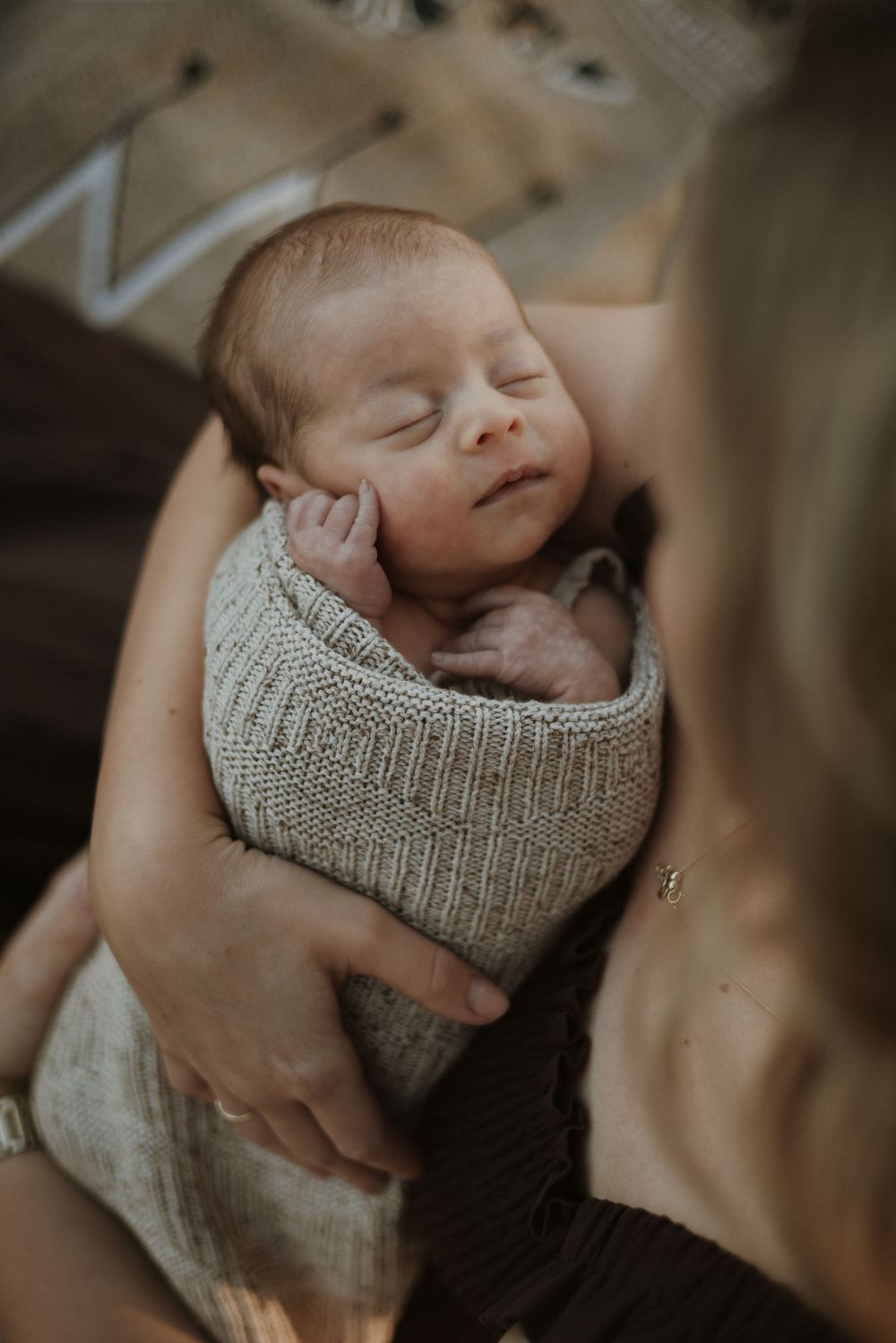 A sleeping newborn baby nestled in a soft gray knit blanket, captured in a series of peaceful close-up shots.