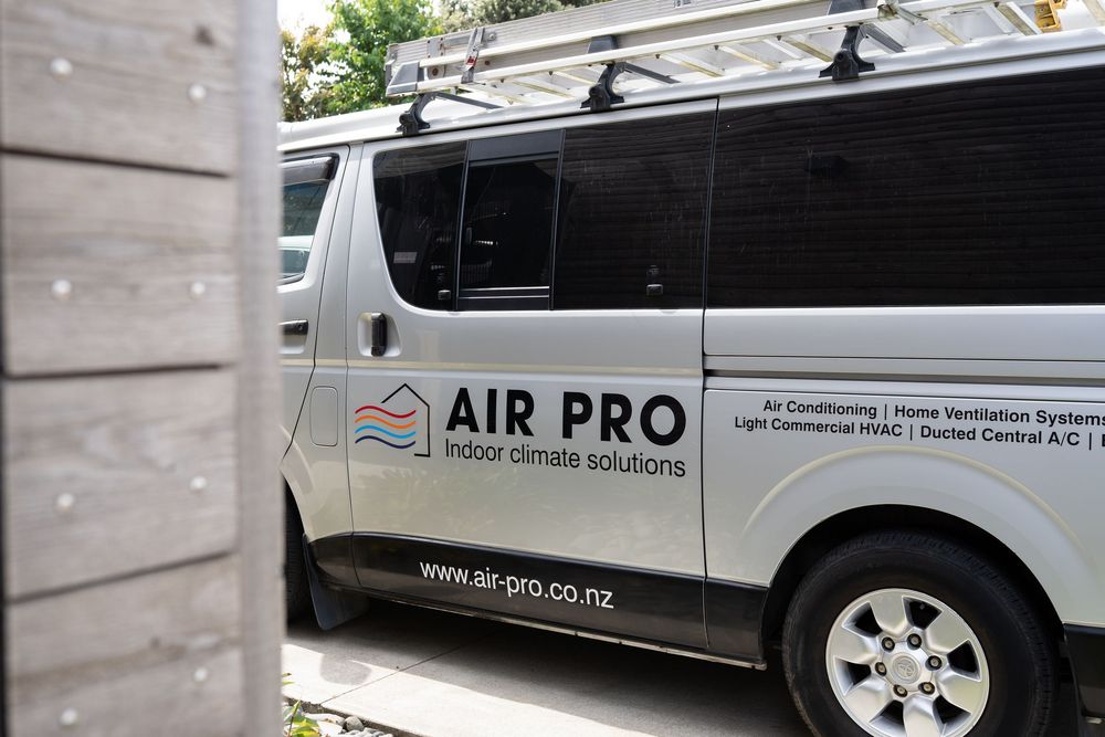 A white commercial van with Air Pro company branding and logo parked on a street.