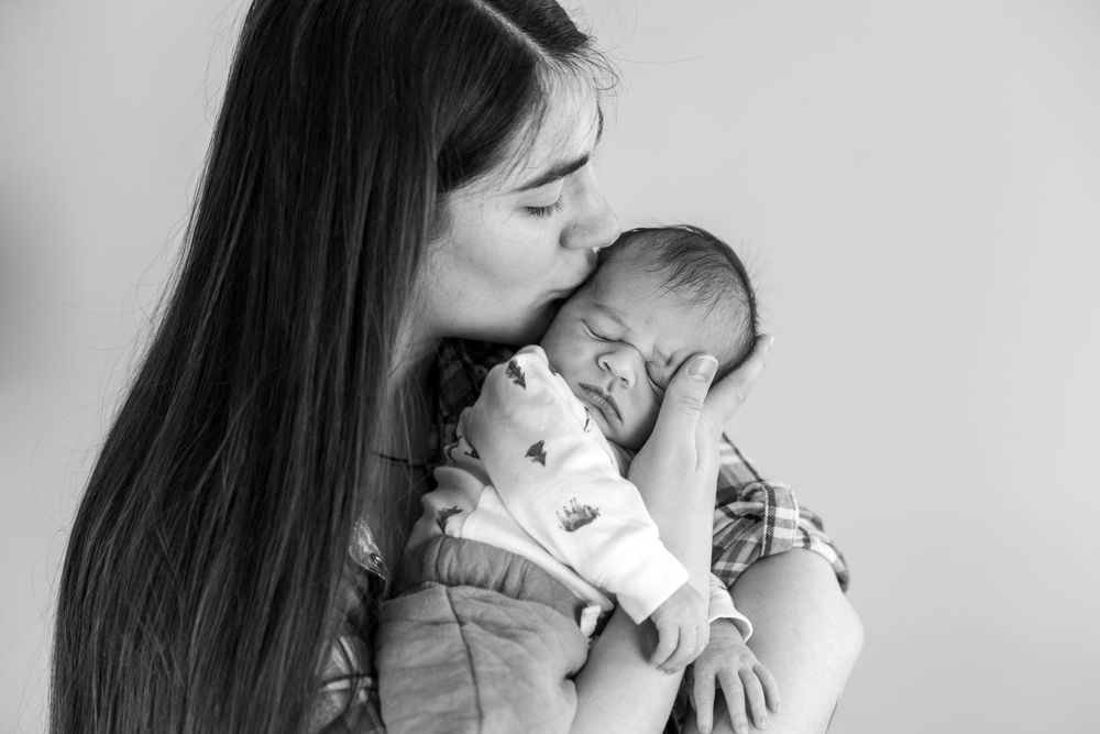 A black and white photo series showing tender moments between a parent and infant in close-up shots.