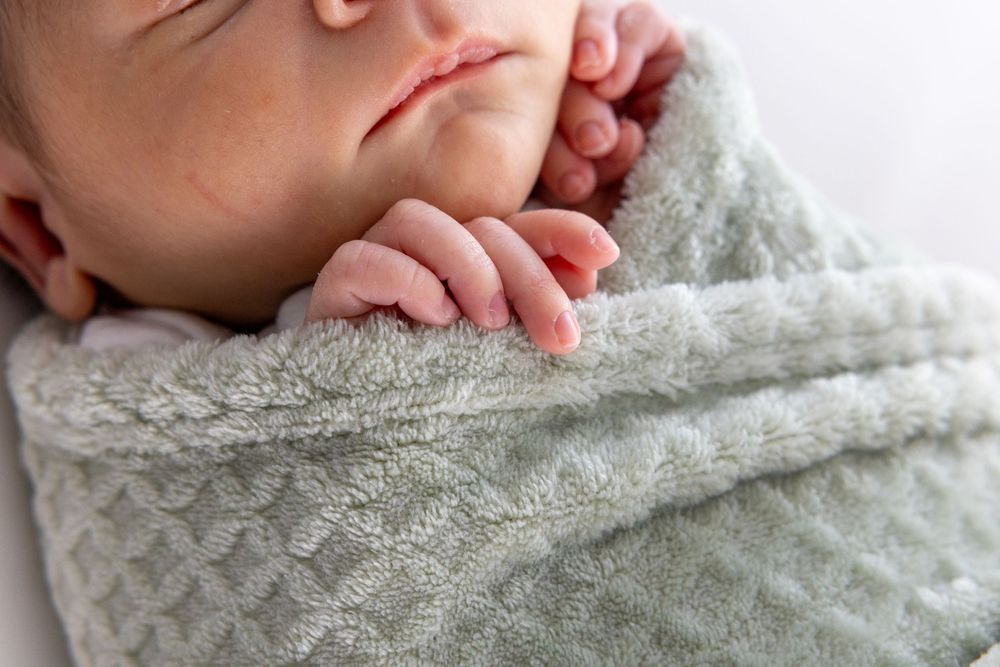 Close-up view of hands resting on soft white textured fabric creating a gentle, peaceful composition.
