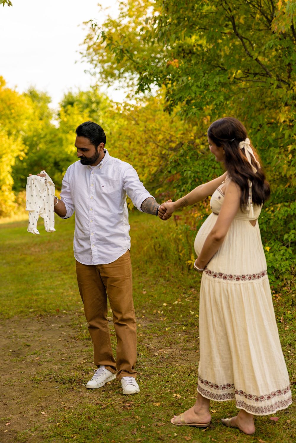 A couple dances together in a scenic autumn setting with golden foliage and warm sunlight.