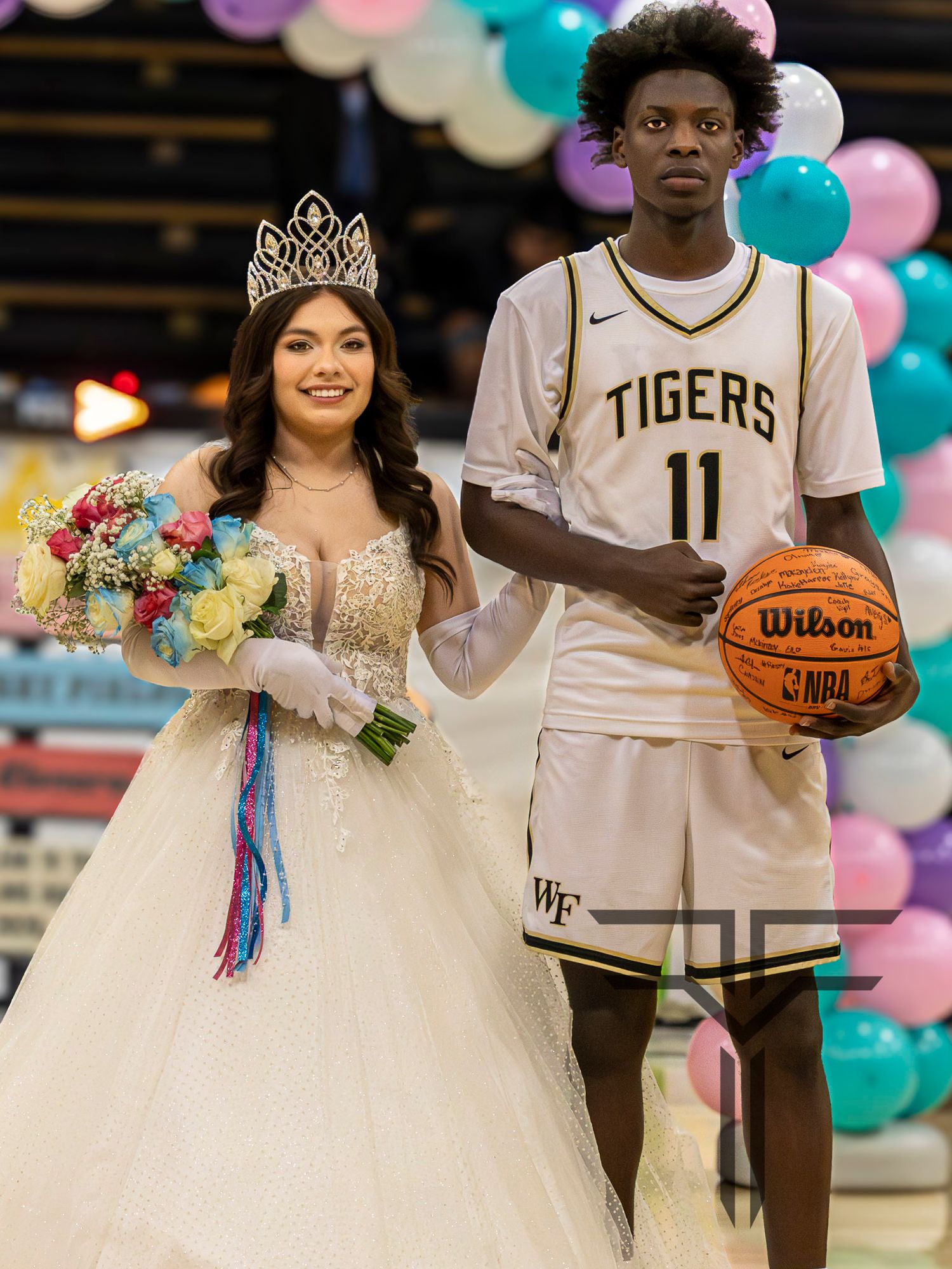 Basketball player in Tigers jersey and person in white wedding dress pose together holding basketball and bouquet.