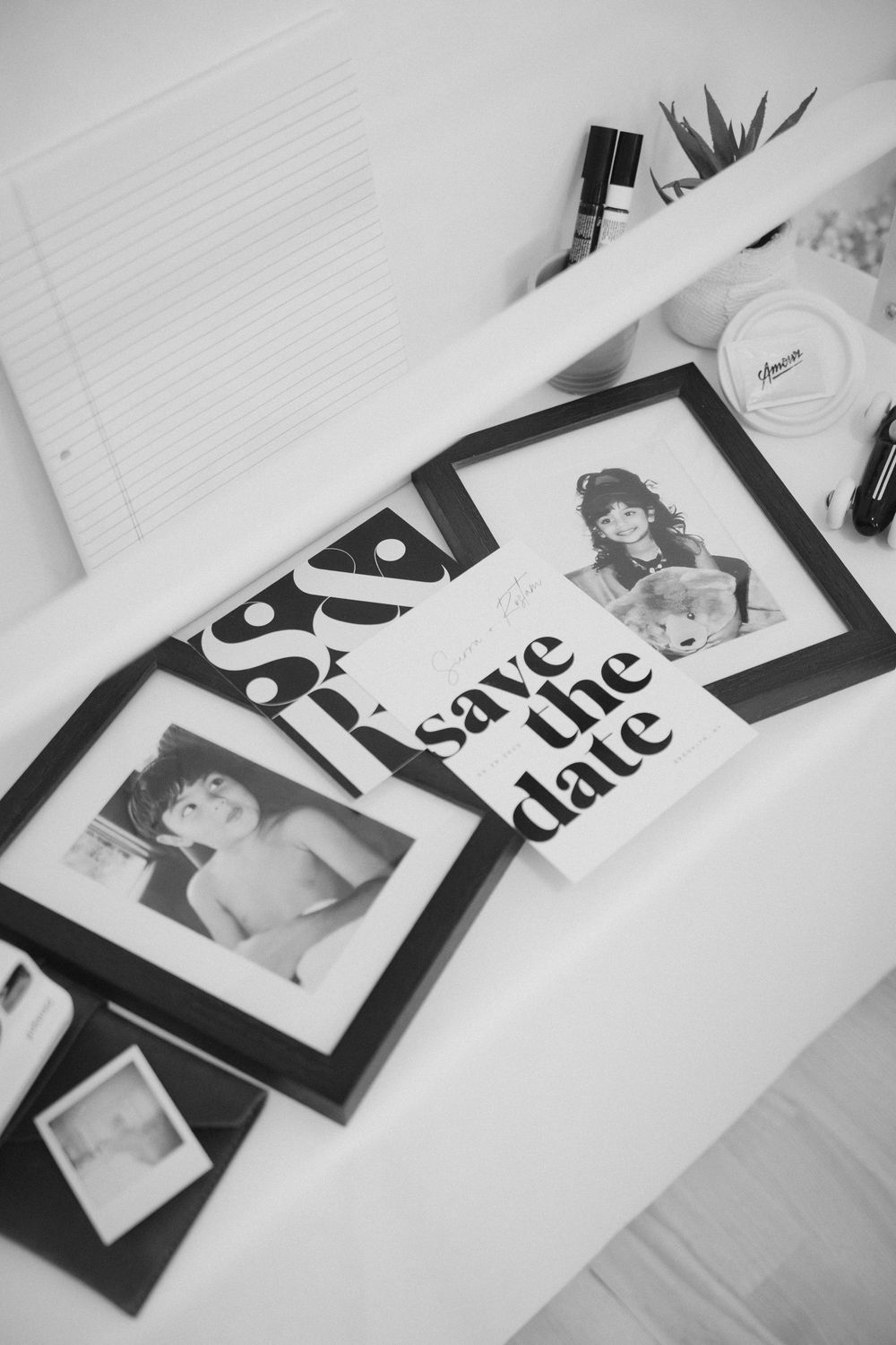Black and white save the date photos arranged on white surface.