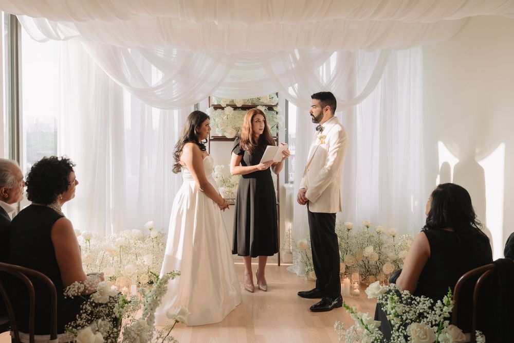 Ethereal wedding ceremony space with flowing white drapes and scattered floral arrangements.
