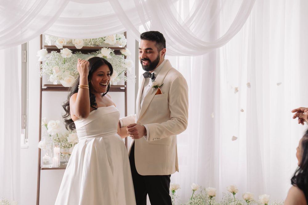 Couple sharing intimate moment during wedding in white draped room with natural light.