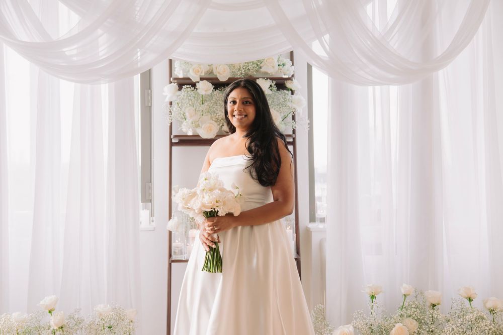 Wedding ceremony space with elegant white draping and floor floral arrangements.