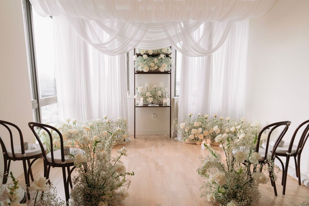 Elegant wedding venue with white drapes and bentwood chairs.