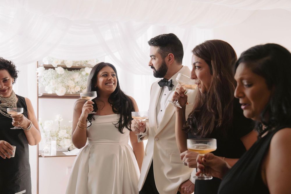 Wedding celebration with guests enjoying drinks in natural light.