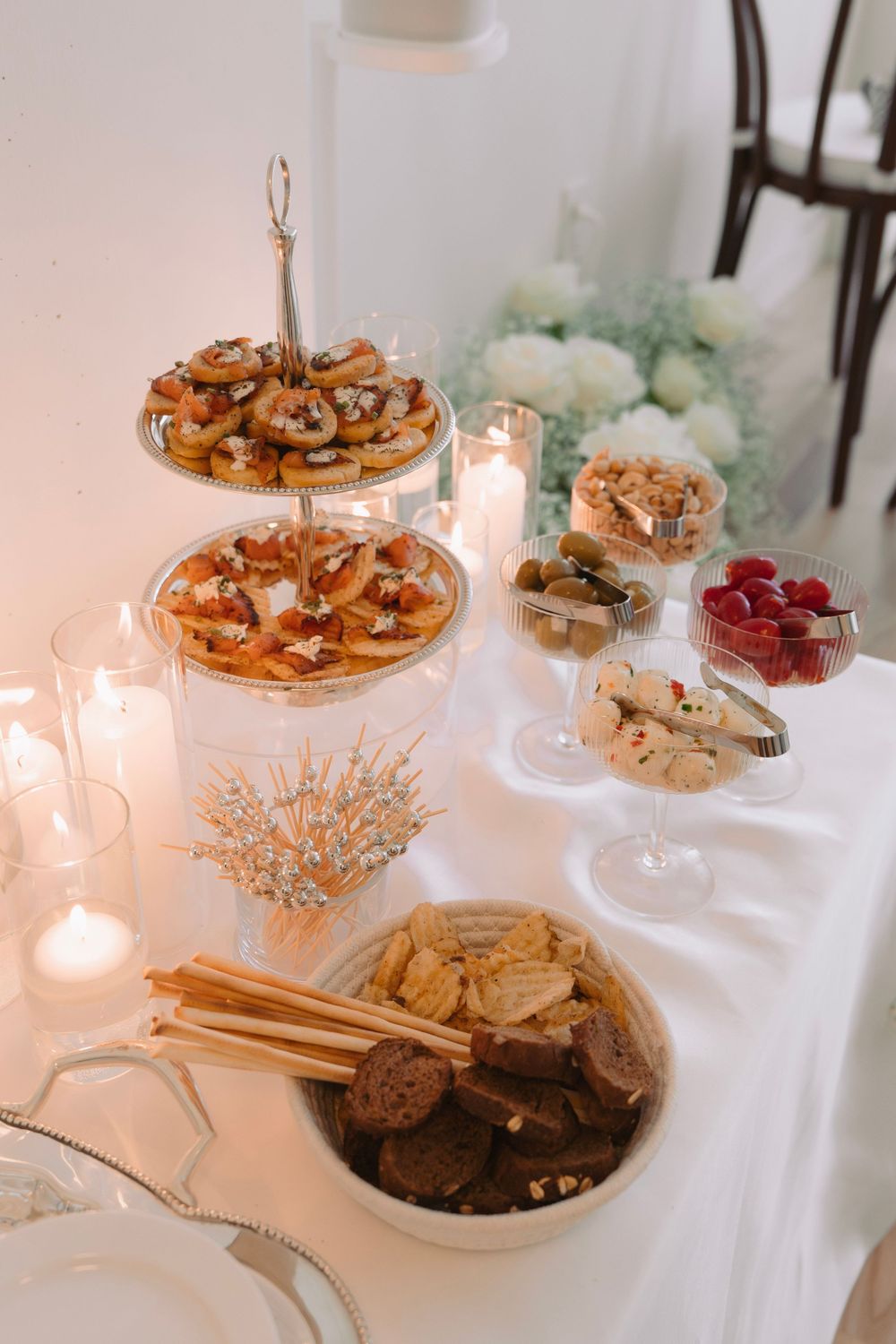 Elegant dessert table with pastries and candles on white tablecloth at wedding reception.