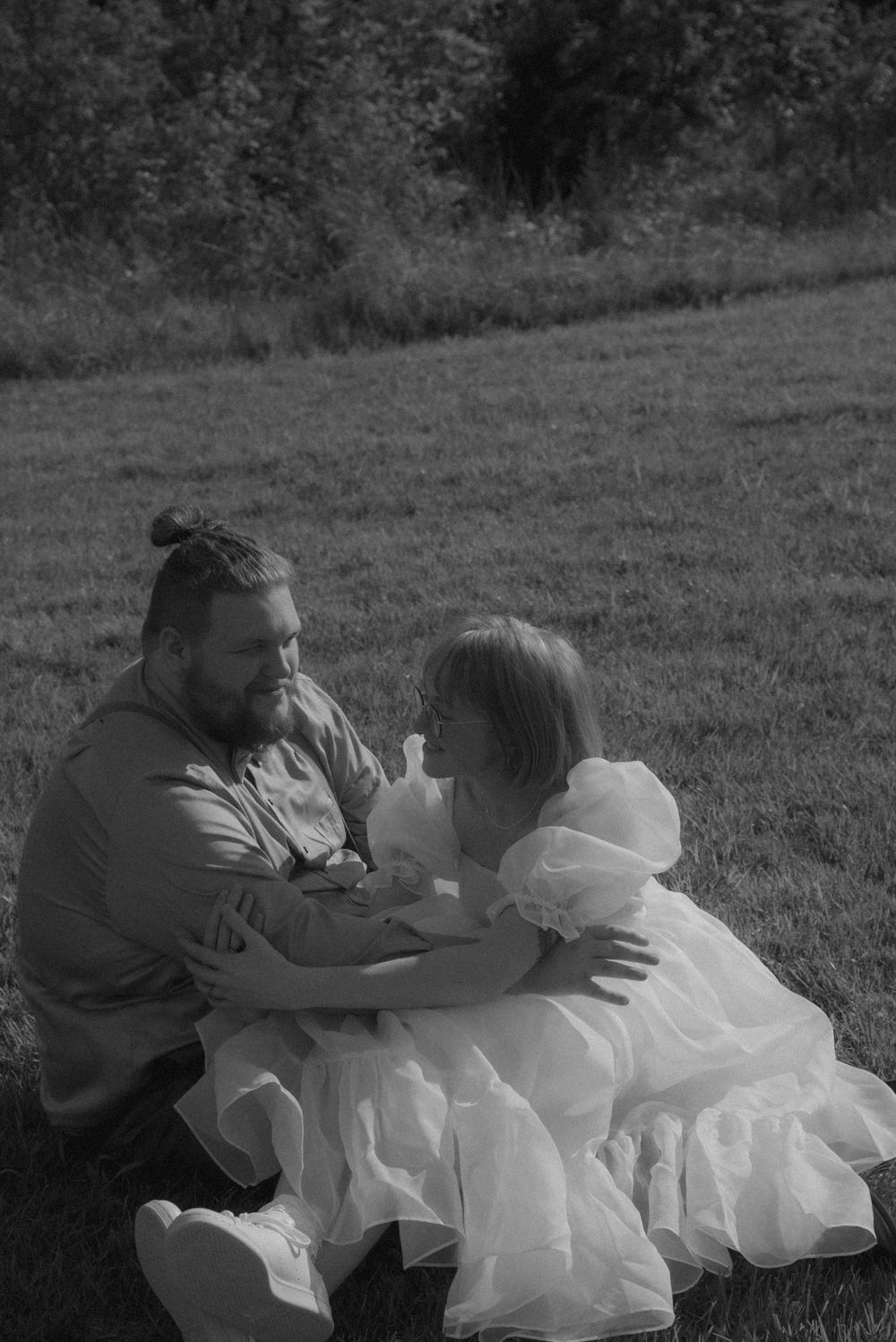 Black and white wedding photography capturing candid moments in a meadow.