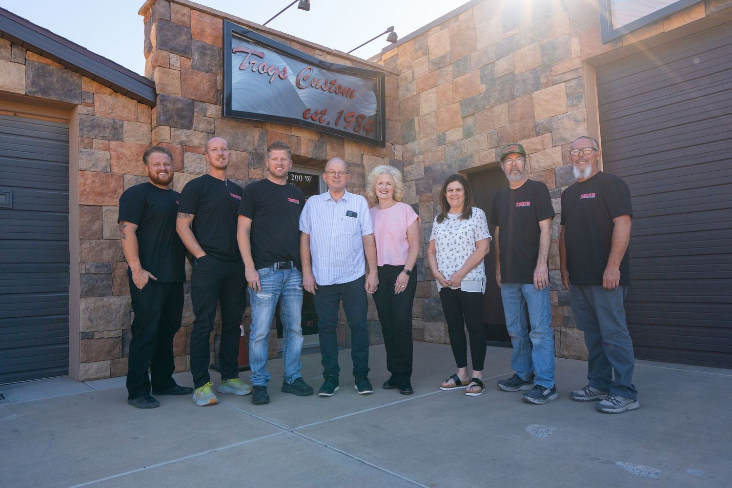 Team photo of staff members standing outside stone building facade.