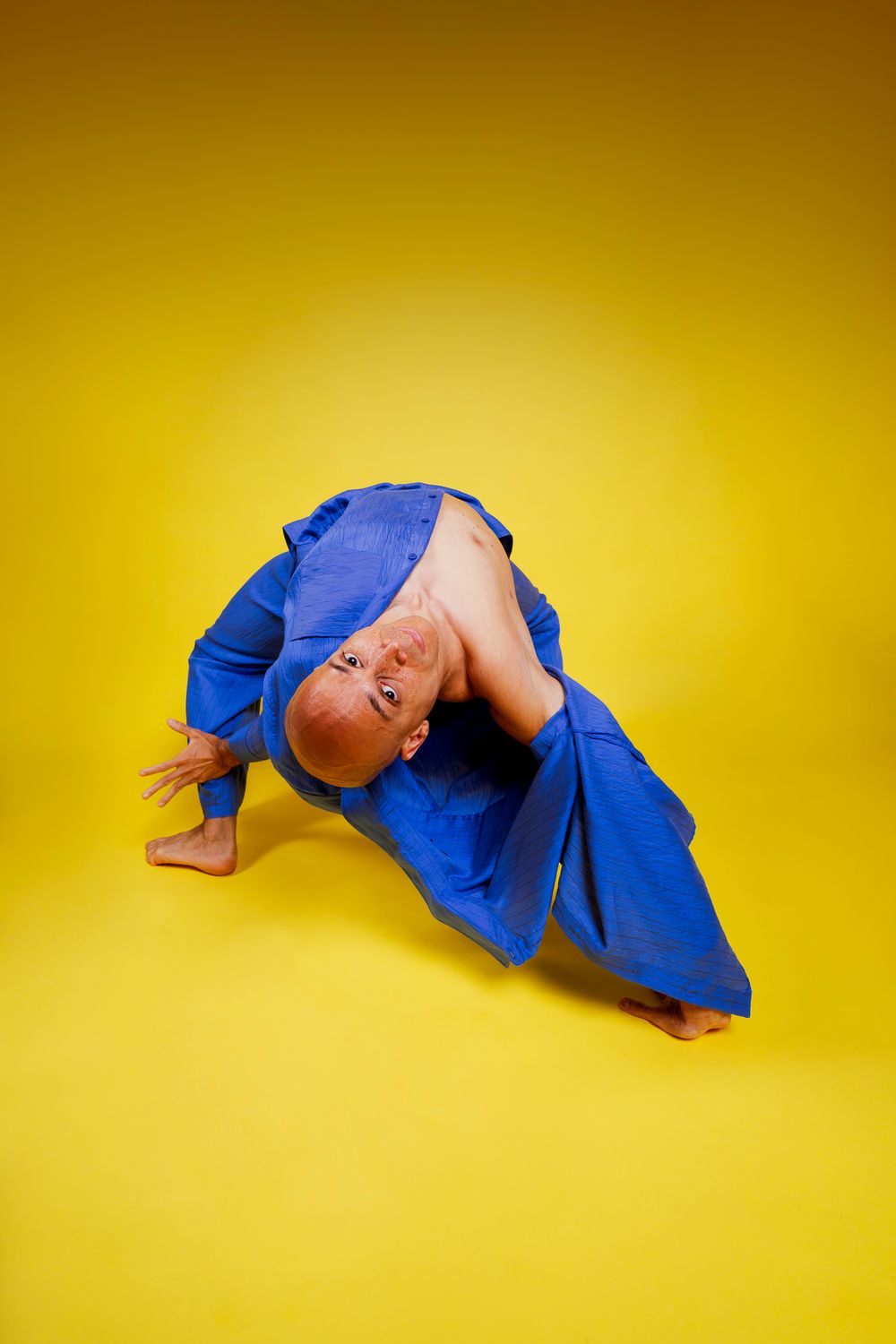 A sequence showing a person in blue judo uniform performing a rolling somersault on a bright yellow background.
