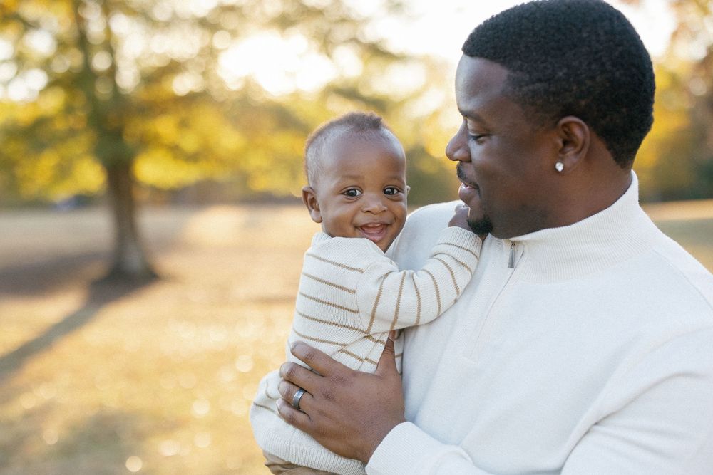 A tender family moment captured against a warm autumn backdrop with fallen leaves.