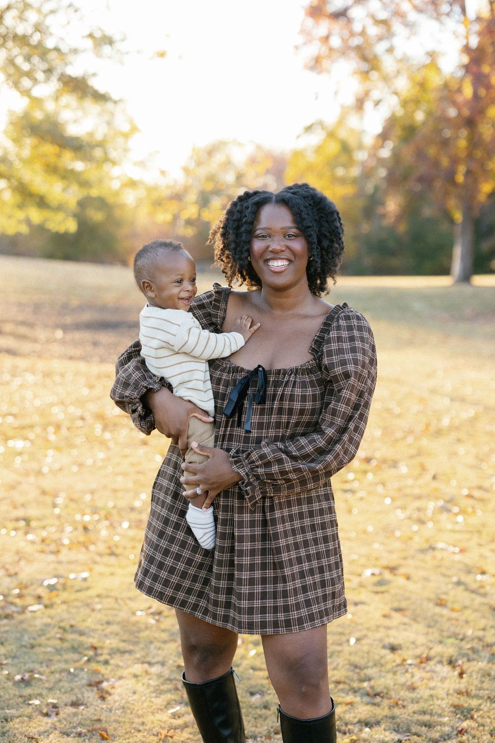 A playful outdoor family photoshoot in a park during golden hour with fall colors.
