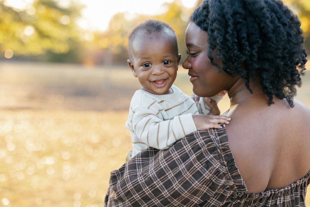 A loving family embraces during a golden hour photoshoot in a sunlit outdoor setting.