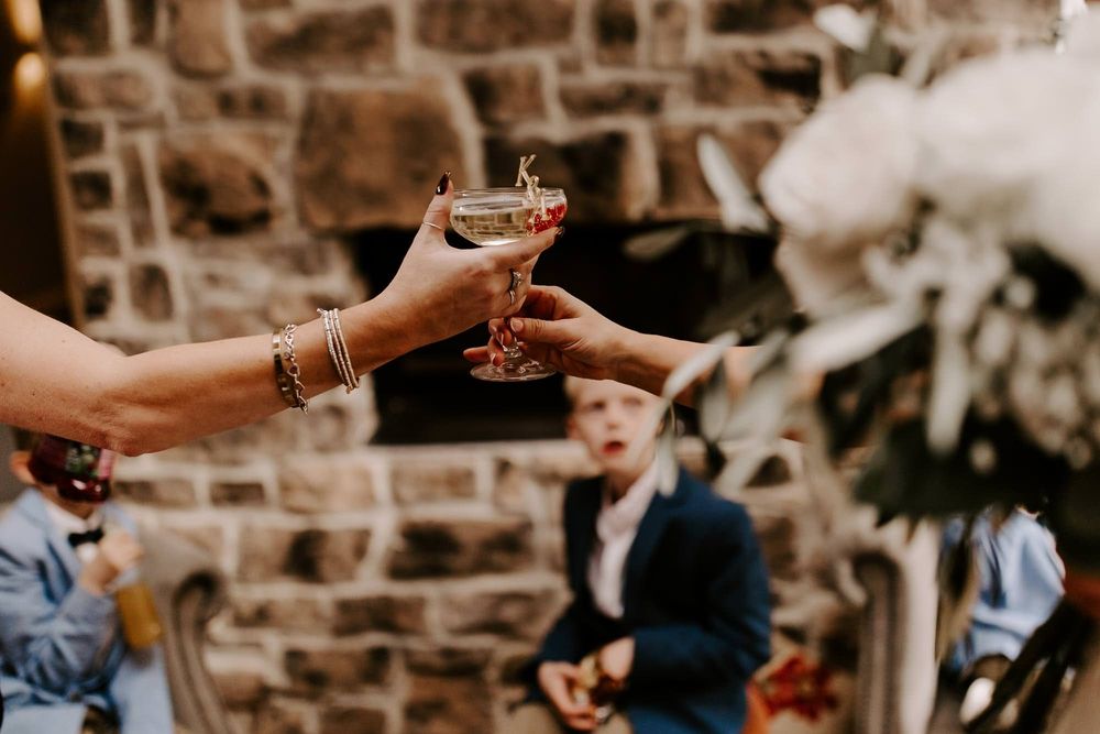 People toasting with wine glasses at a rustic brick wall venue during a celebration event.