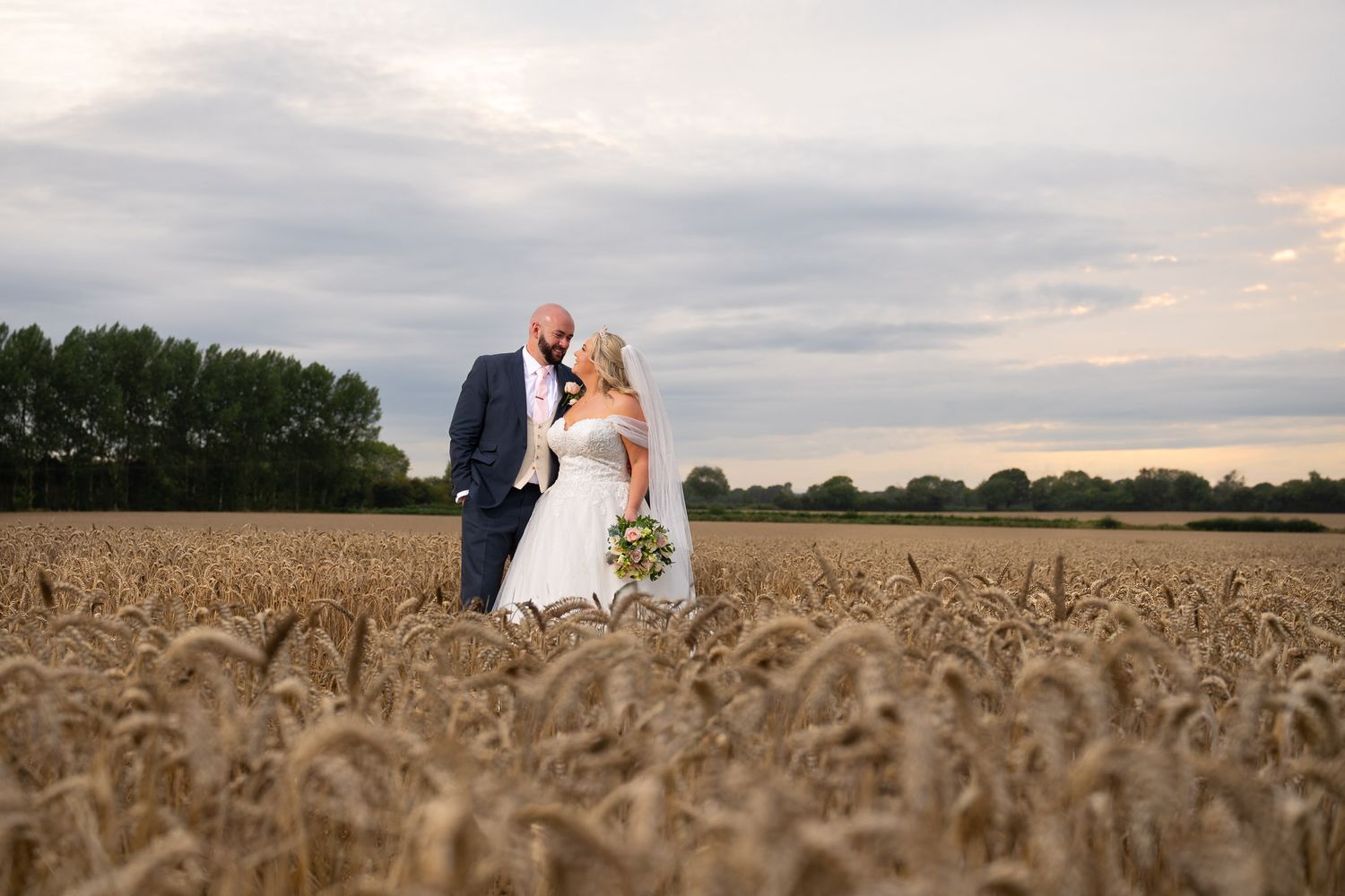 A romantic wedding couple poses at night in front of an illuminated white gazebo in a dramatic lighting setup.