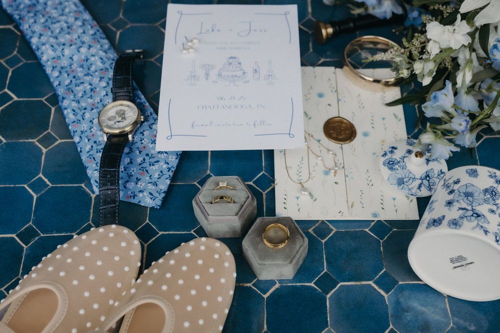 Wedding reception table decorated with blue and white floral patterns, sketches, and elegant place settings.
