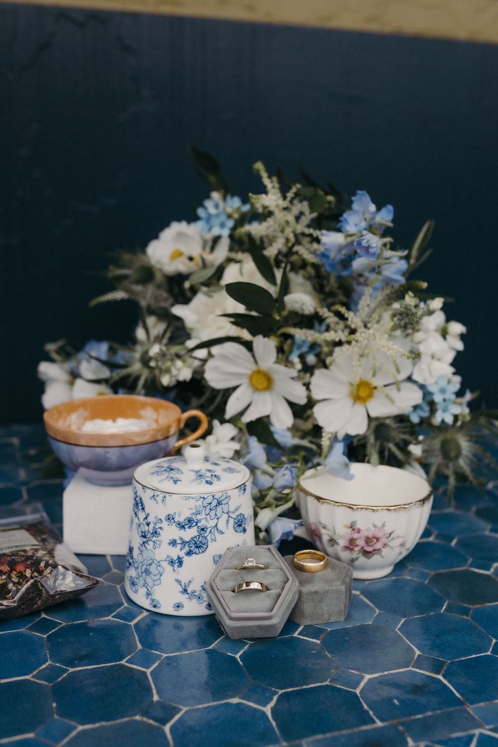 Vintage teacups and floral arrangements displayed on a blue tiled surface.