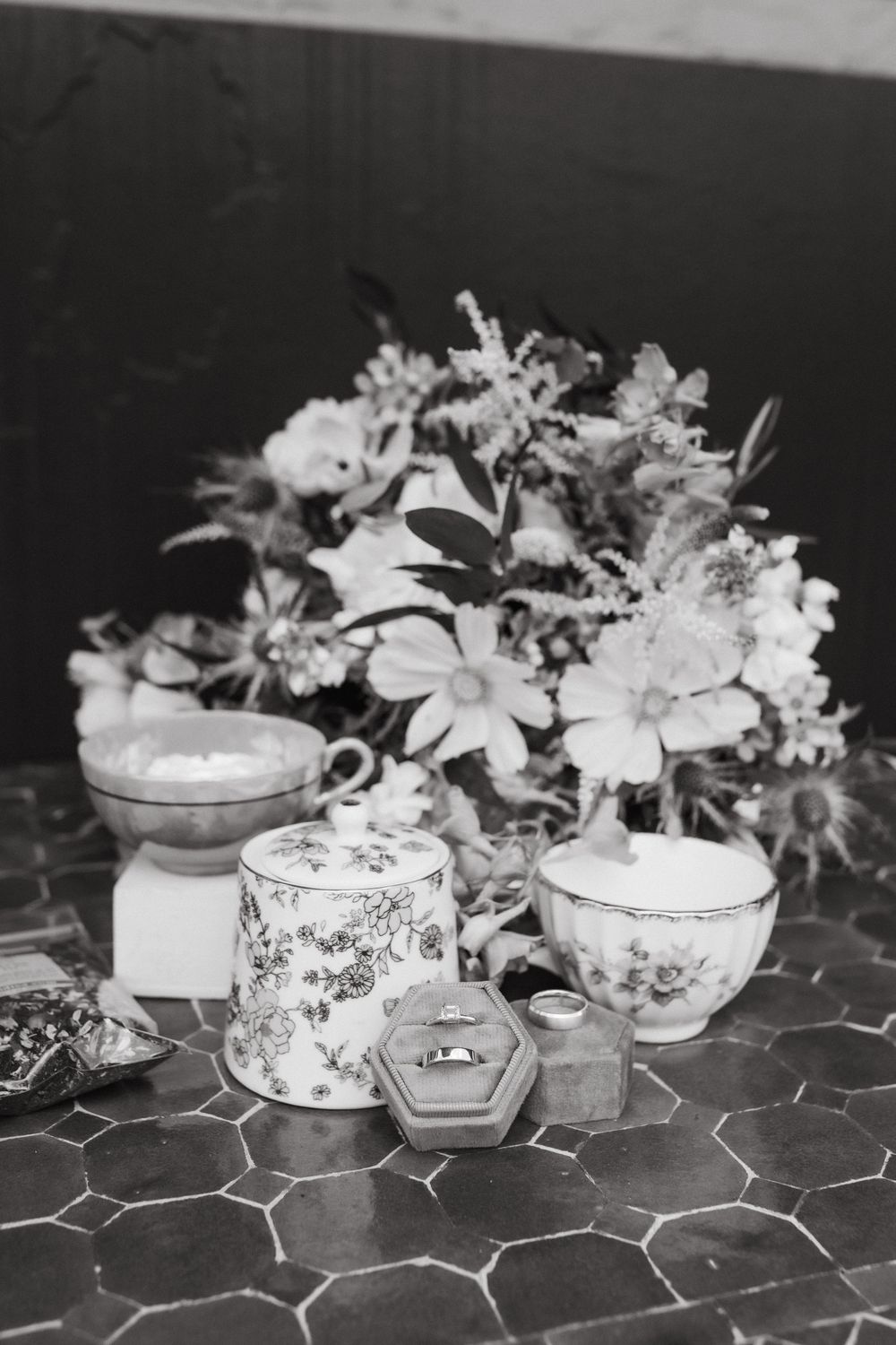 Vintage-style decorative teacups and floral arrangements displayed on a patterned tablecloth.