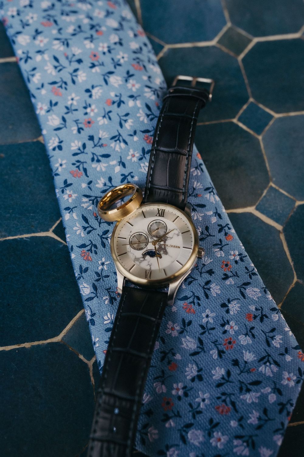Elegant wristwatch with leather band resting on blue floral fabric.