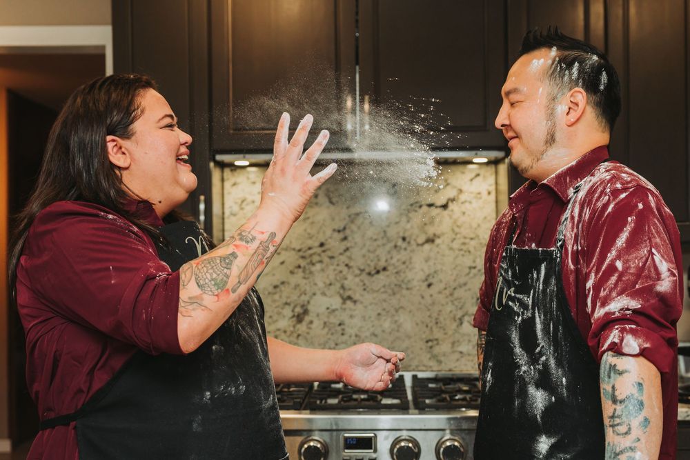 A group of people in burgundy uniforms laughing and interacting in a kitchen setting.