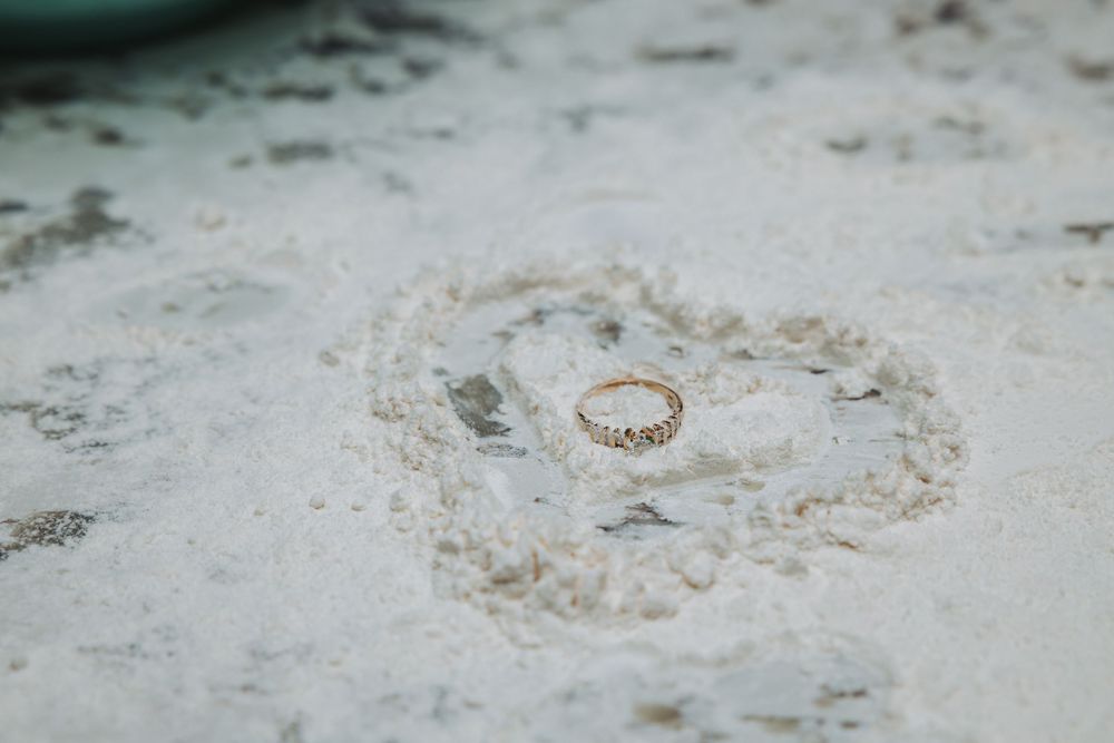 Macro shot of delicate white lace wedding dress fabric with intricate floral patterns and embroidered details.