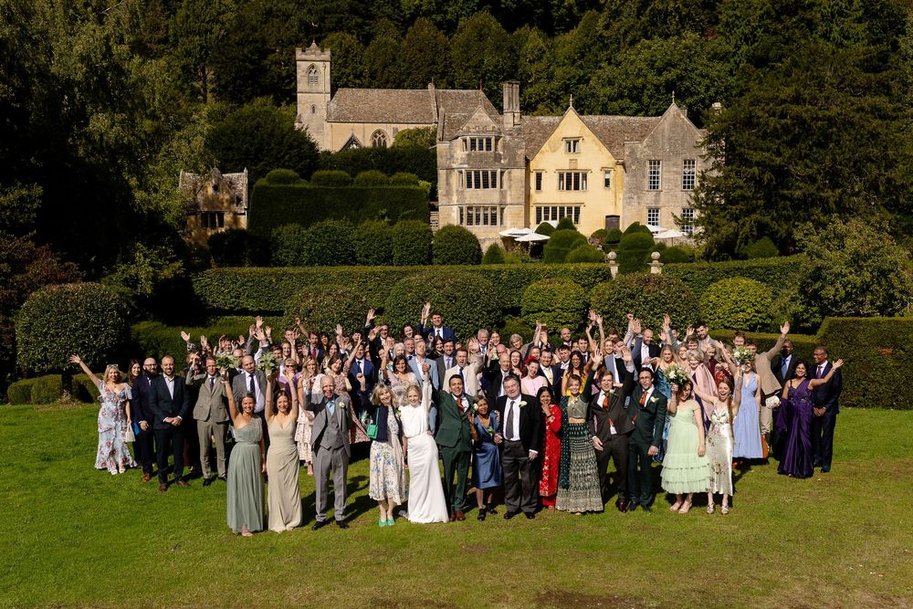 Large wedding party group photo taken in front of a grand stone mansion.