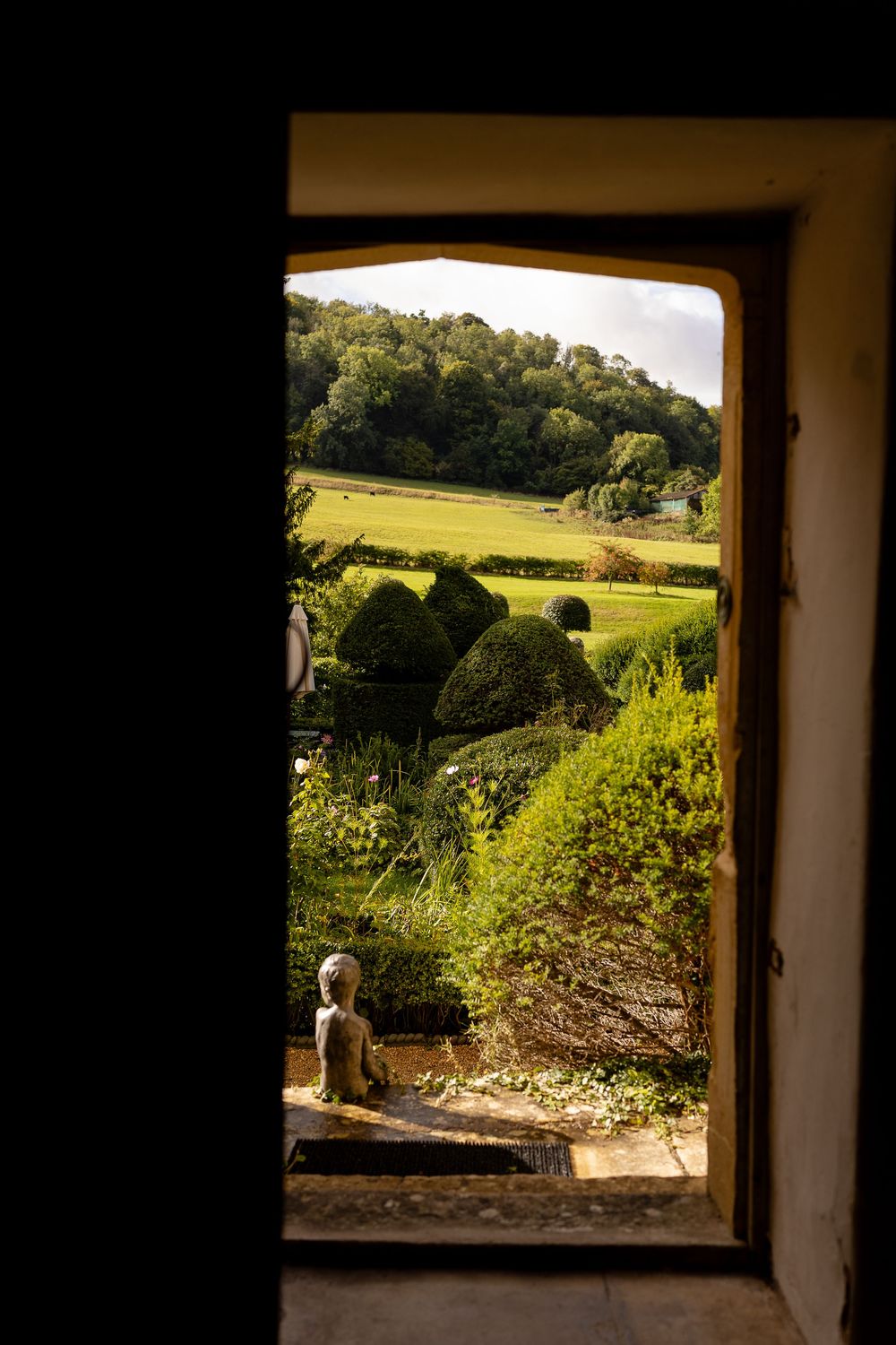 Sequence of window frames overlooking a scenic green countryside landscape with rolling hills and manicured gardens.