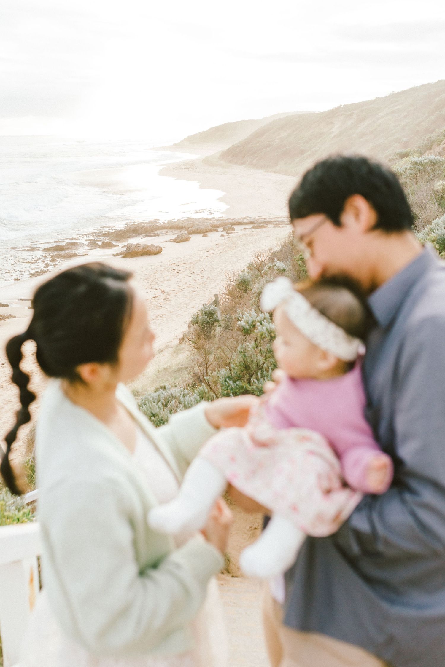 A romantic couple shares tender moments on a beach at sunset with soft lighting and natural coastal scenery.