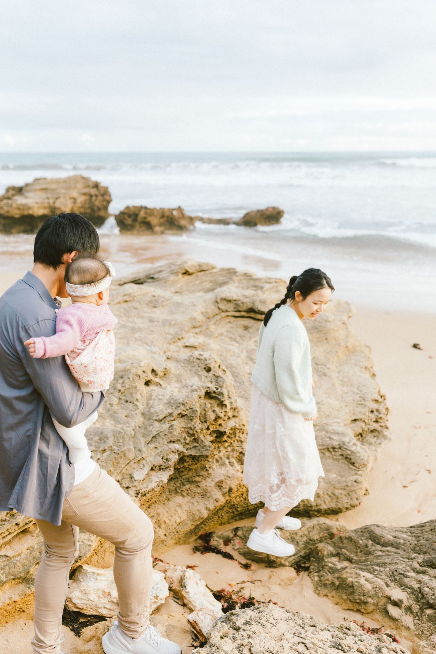 Two people enjoy a tender embrace while standing on coastal rocks near the ocean.