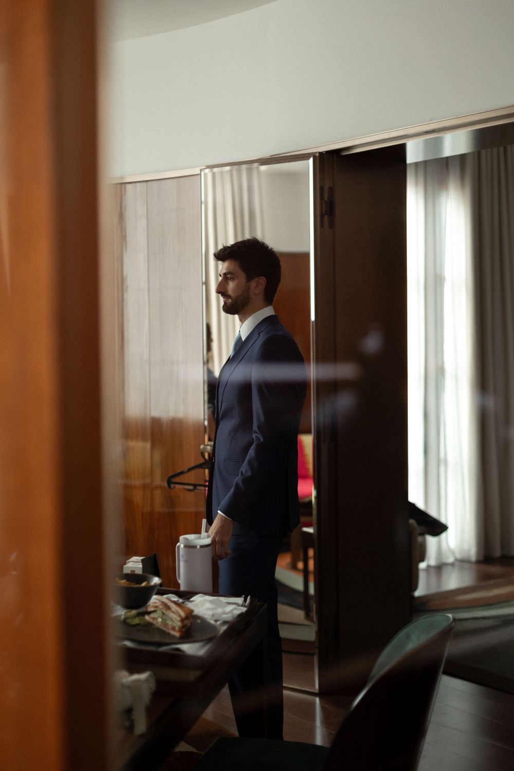 A sequence of photos showing a person in a navy suit standing by a window in a hotel room.