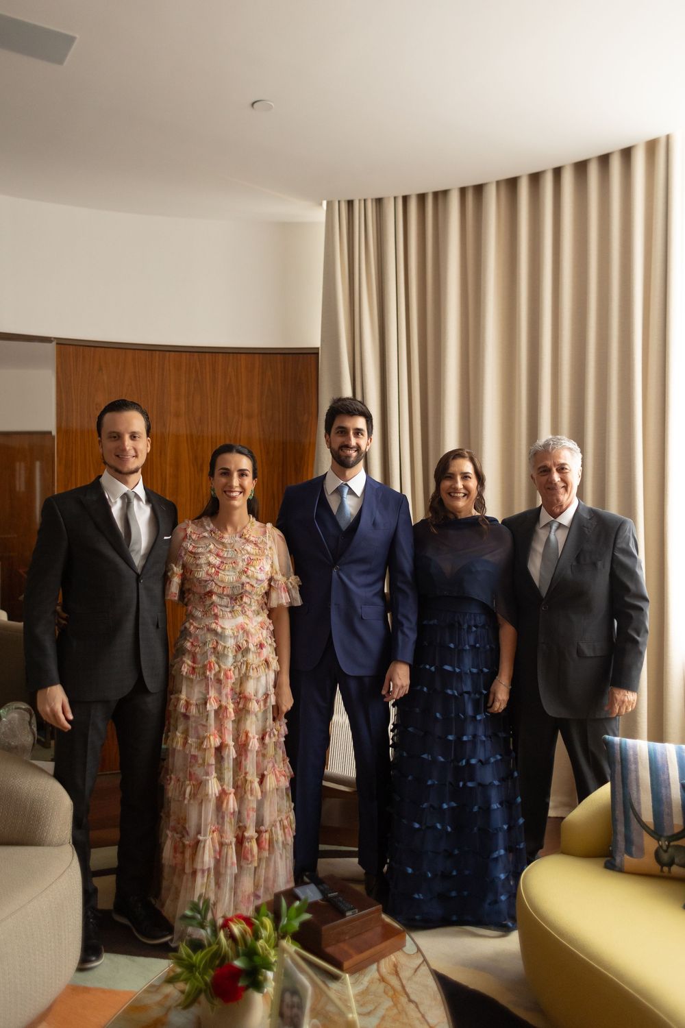 A group photo showing people dressed formally in suits and dresses gathered in a hotel room.