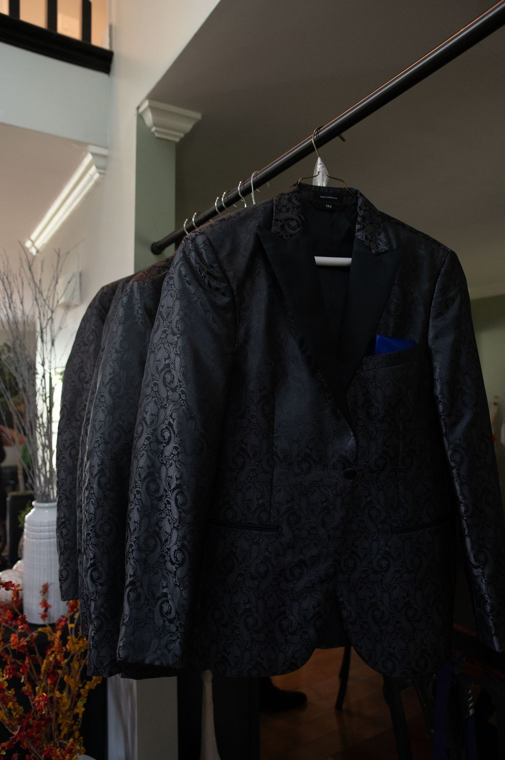 Black lace jacket displayed on hangers in a retail setting with decorative branches in the background.