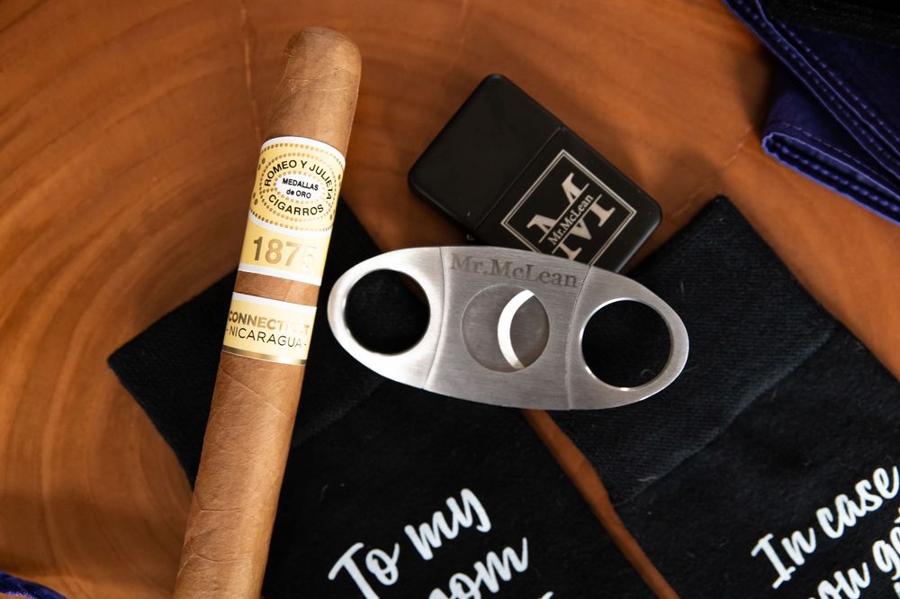 Cigars and chalk boards displaying drink menu items arranged on a wooden surface with dark lighting.