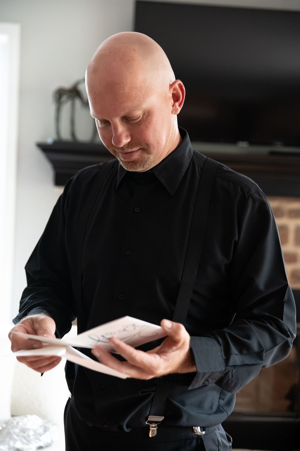 A chef in a black uniform carefully reviews notes in a small notebook while working in a professional kitchen setting.