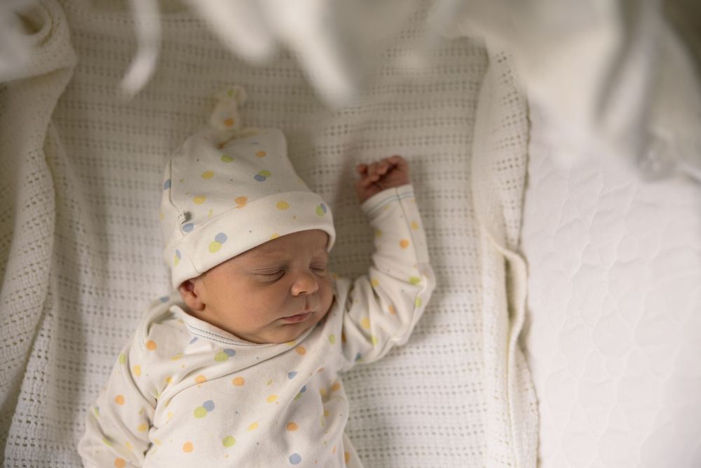 A sleeping infant lies peacefully in white bedding under decorative blocks.