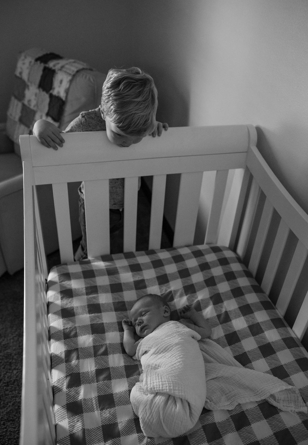 Baby sleeping peacefully in white crib with buffalo check bedding.
