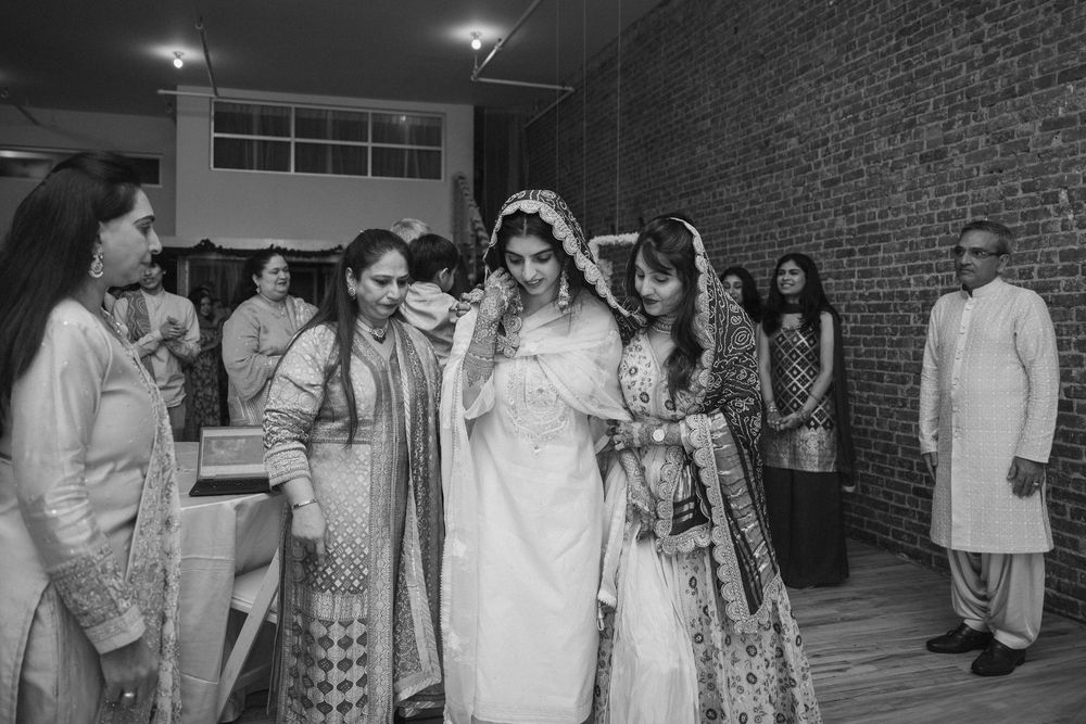 Black and white photo of wedding guests gathered for a celebration in traditional Indian attire.