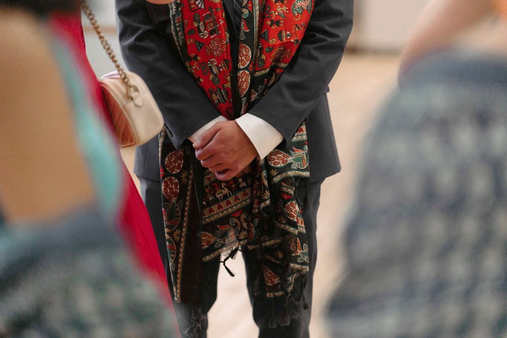 Detail shot of traditional Indian formal wear with intricate embroidery patterns on dark fabric.