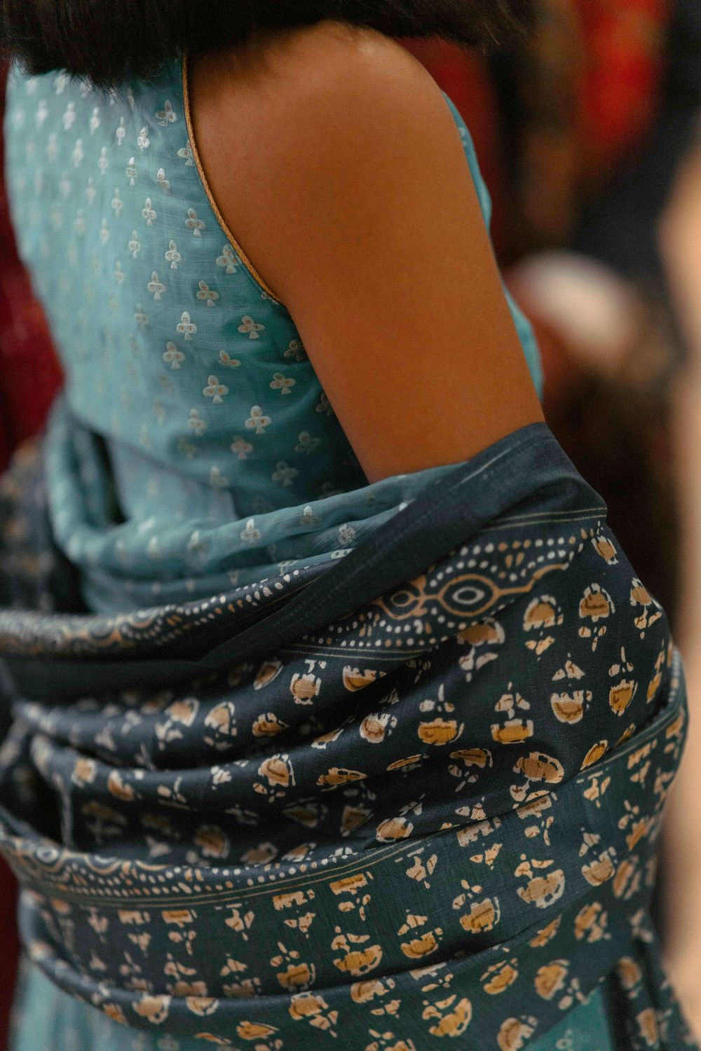 Close-up of a turquoise and navy blue traditional Indian sari with delicate floral patterns and embroidery details.