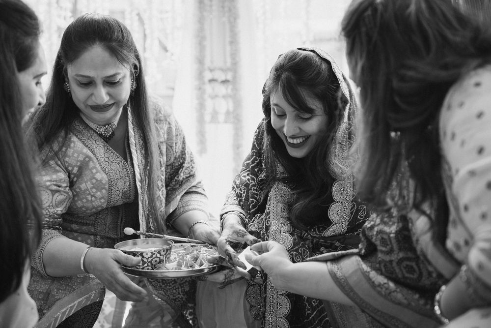 Group of women in traditional Indian attire sharing a plate of food during a celebration.