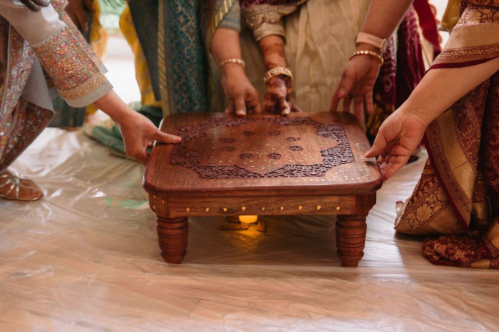 Hands reaching for an ornate wooden ceremonial platform during a traditional Indian ritual.