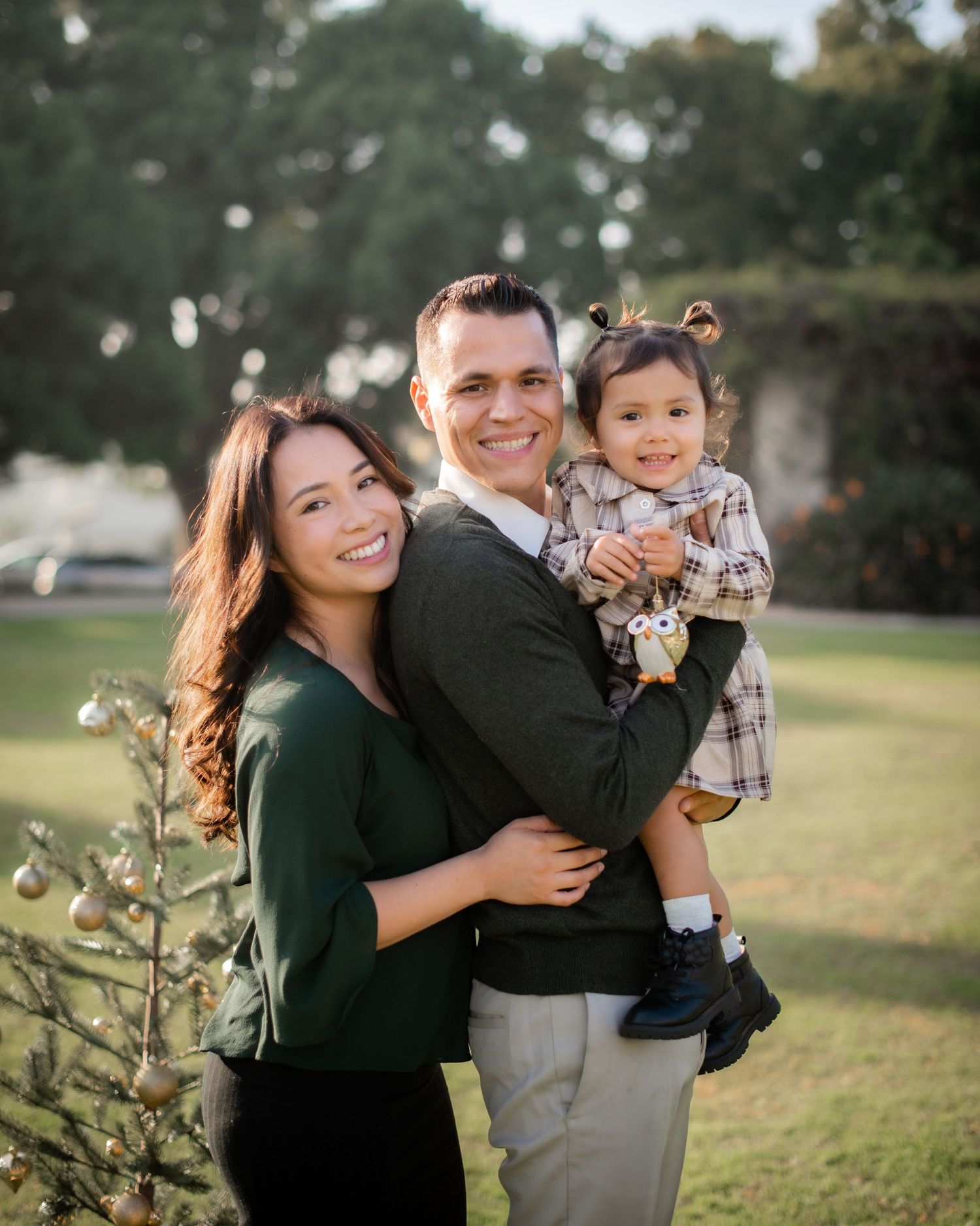 A family shares joyful moments together in a grassy outdoor setting during a golden hour photoshoot.