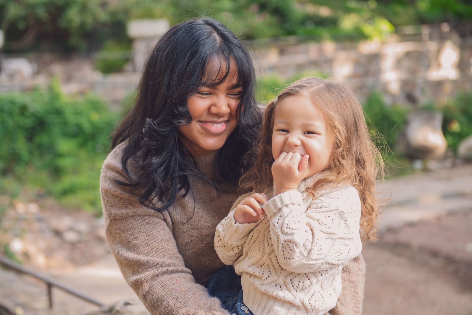 Two people share a joyful moment together outdoors in a natural setting with blurred greenery in the background.