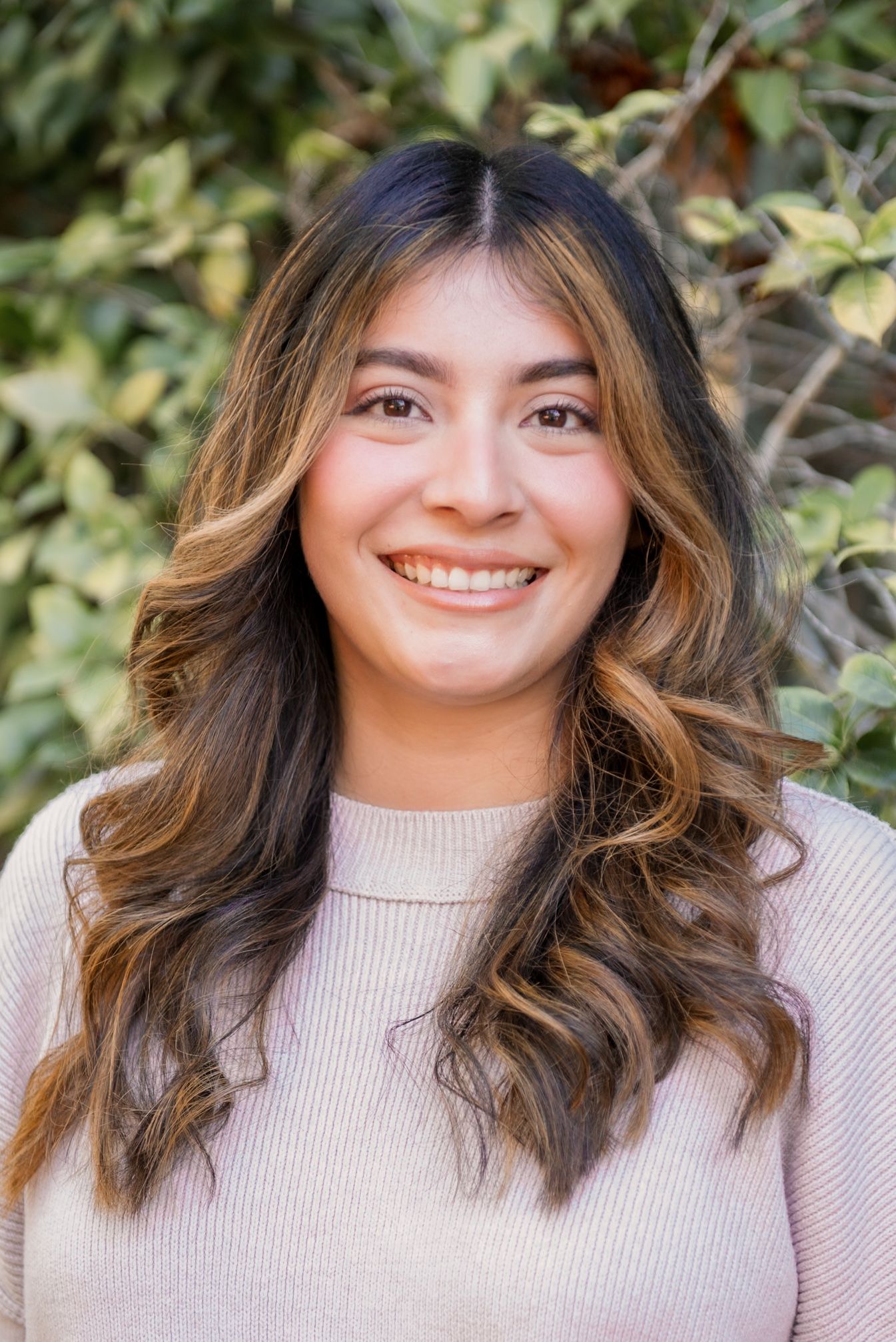 A series of portraits showing someone with wavy brown hair wearing a beige sweater smiling at the camera.