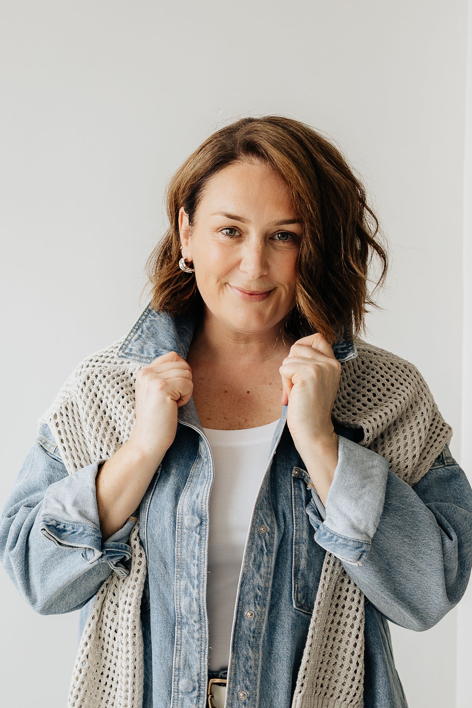 Four sequential photos show someone wearing a denim jacket and knit scarf posing playfully against a white background.
