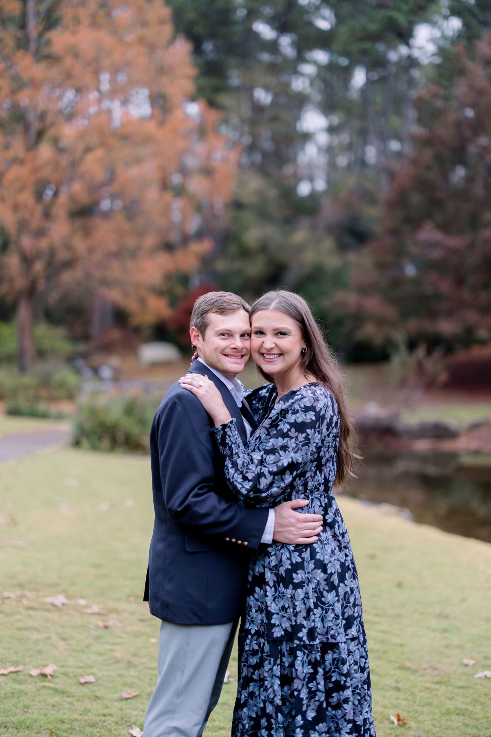 Couple sharing a romantic moment in a park during fall with orange leaves in the background.