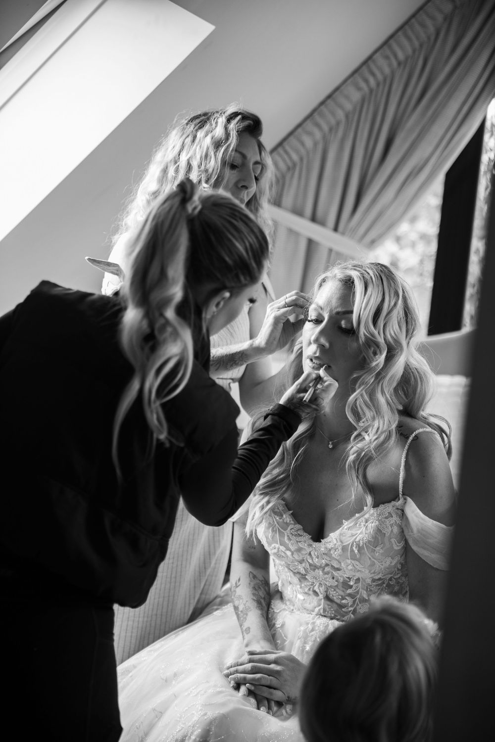 Black and white emotional wedding preparation moment showing bride and loved ones sharing intimate embrace.