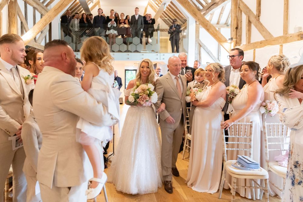 Wedding ceremony taking place in a rustic wooden barn venue with guests seated in rows.